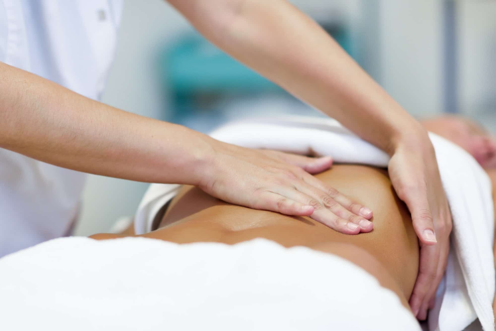 Woman having abdomen massage by professional osteopathy therapis